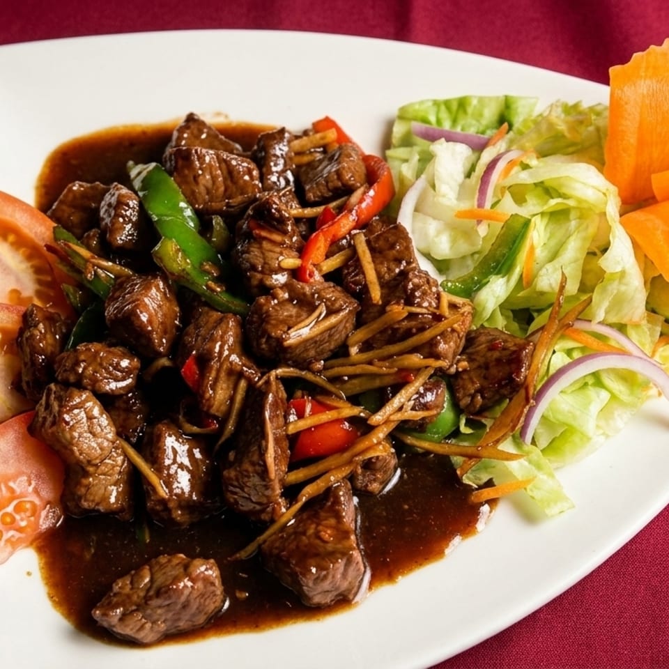 Savory beef stir-fry with bell peppers, ginger, and a side salad with carved carrot garnish.